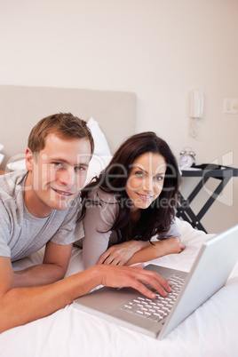 Smiling couple using laptop in the bedroom together