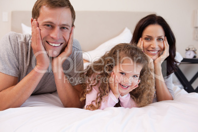 Smiling family lying on the bed together