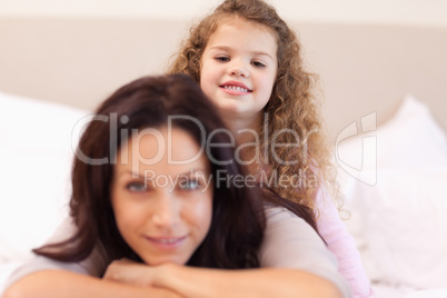Smiling girl sitting on her mothers back