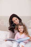Mother and daughter reading a book on the bed
