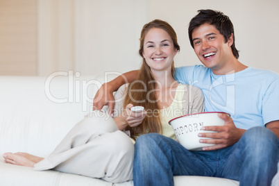 Couple watching television while eating popcorn