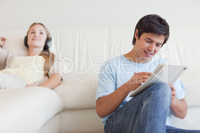 Man doing crosswords while his fiance is listening to music