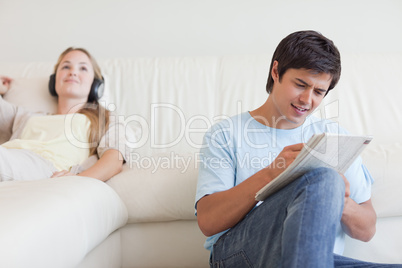 Man doing crosswords while his wife is listening to music