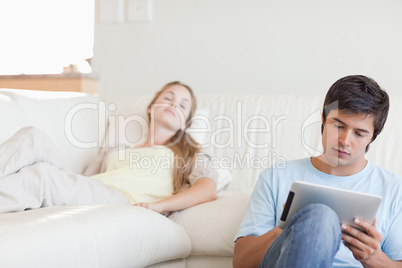 Man using a tablet computer while his girlfriend is sleeping