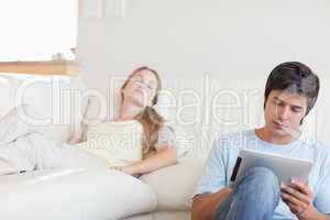 Man using a tablet computer while his girlfriend is sleeping