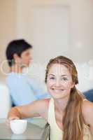 Portrait of a woman having a coffee while her husband is sitting