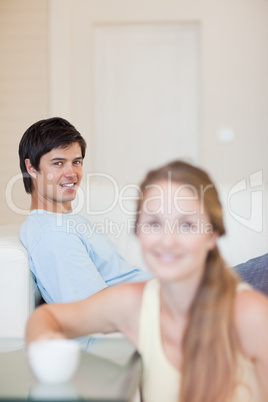 Portrait of a woman having a tea while her fiance is sitting on