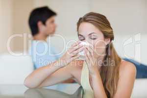 Woman drinking tea while her fiance is sitting on a sofa