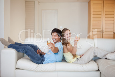 Couple sitting back to back with a glass of sparkling wine