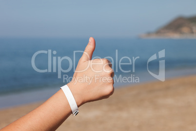 Hand gesturing thumb up on sea beach