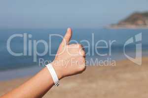 Hand gesturing thumb up on sea beach