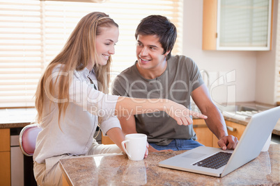 Smiling couple having coffee while using a notebook