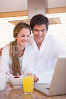 Portrait of a couple having breakfast while using a notebook