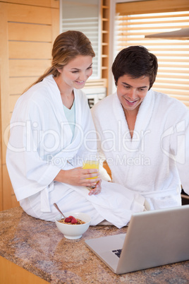 Portrait of a young couple having breakfast while using a laptop