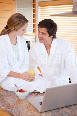 Portrait of a lovely couple having breakfast while using a noteb