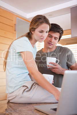 Portrait of a couple having coffee while using a laptop