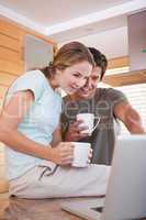 Portrait of a young couple having tea while using a laptop