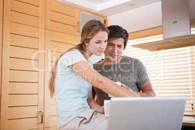 Young couple having tea while using a laptop