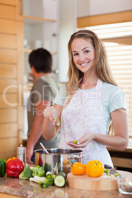 Portrait of a woman cooking while her fiance is washing the dish