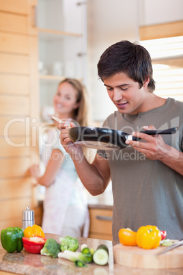 Portrait of a man cooking while his fiance is washing the dishes