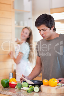 Portrait of a man cooking while his wife is washing the dishes