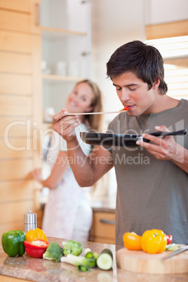 Portrait of a man cooking while his girlfriend is washing the di