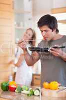 Portrait of a man cooking while his girlfriend is washing the di