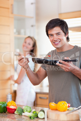 Portrait of a young man cooking while his wife is washing the di