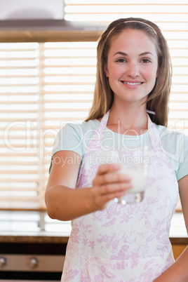 Portrait of a young woman giving a glass of milk