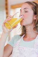 Portrait of a delighted woman drinking orange juice