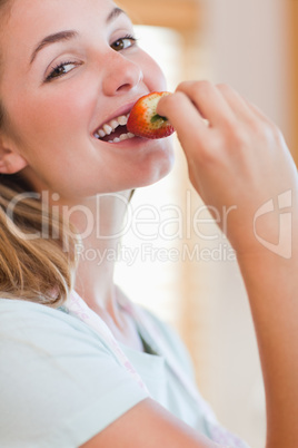 Close up of a young woman eating a strawberry