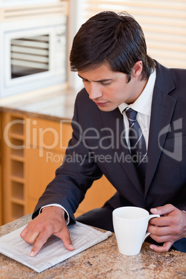 Portrait of a businessman drinking coffee while reading a newspa