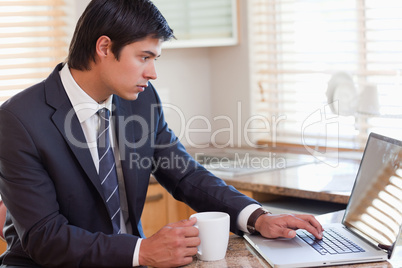 Man working with a laptop while drinking coffee