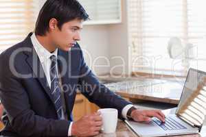 Man working with a laptop while drinking coffee