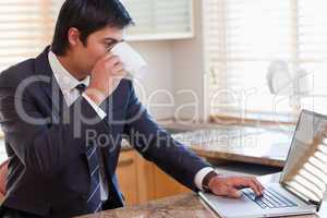 Man working with a laptop while drinking tea
