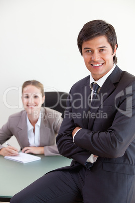 Portrait of a businessman posing while his colleague is working