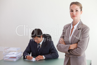 Busineswosman posing while her colleague is working