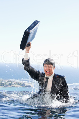 Portrait of a young businessman going out of the water with a br