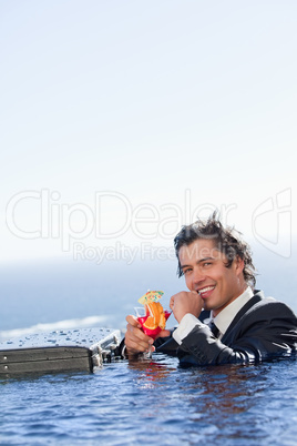 Portrait of a smiling businessman relaxing in a swimming pool wi