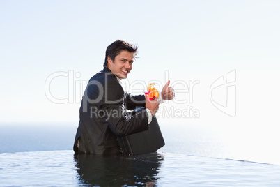 Portrait of a businessman posing with a cocktail and a briefcase