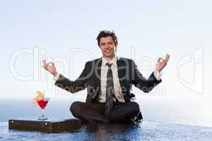 Smiling businessman relaxing in the lotus position