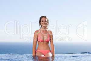Smiling woman sitting by a swimming pool