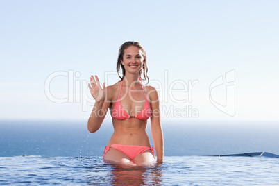 Young woman sitting by a swimming pool