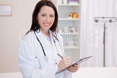 Smiling female physician taking notes