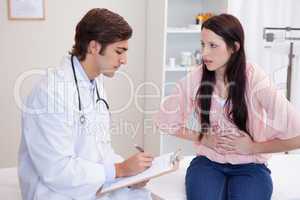 Male doctor writing down female patients symptoms