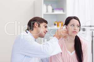 Male doctor examining his patients ear
