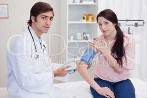 Doctor taking female patients blood pressure