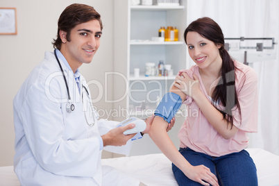 Smiling doctor taking patients blood pressure