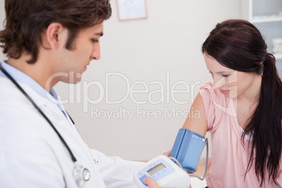 Male doctor taking female patients blood pressure