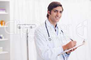 Side view of smiling doctor taking notes